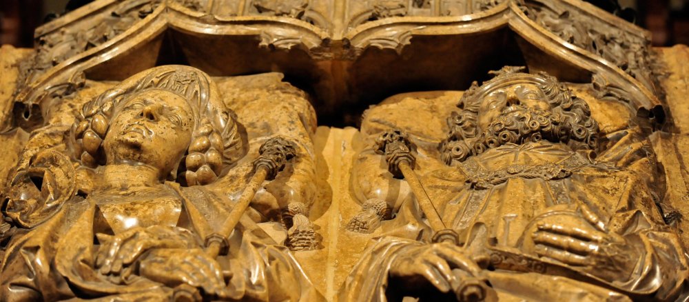Ein Paar mit kaiserlichen Herrschaftssymbolen liegt als Mamrmor-Relief auf einem Grab. Es handelt sich um das Kaisergrab im Bamberger Dom.