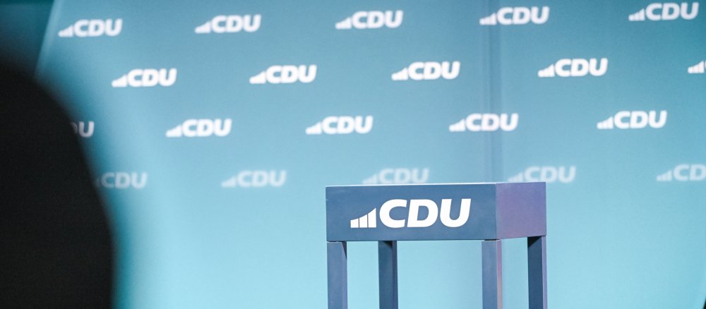 Logos der Partei CDU an einem Stehtisch und im Hintergrund bei einer Wahlkampfveranstaltung