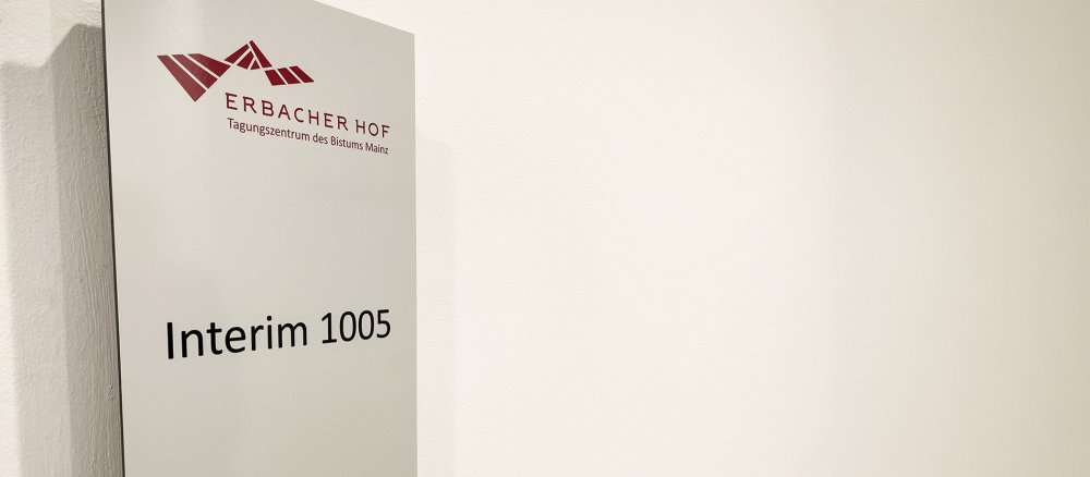 Schild eines Tagungsraums im Tagungshaus Erbacher Hof in Mainz ist am 27. November 2025 vom Namen eines kirchlichen Würdenträgers zu "Interim" geändert.