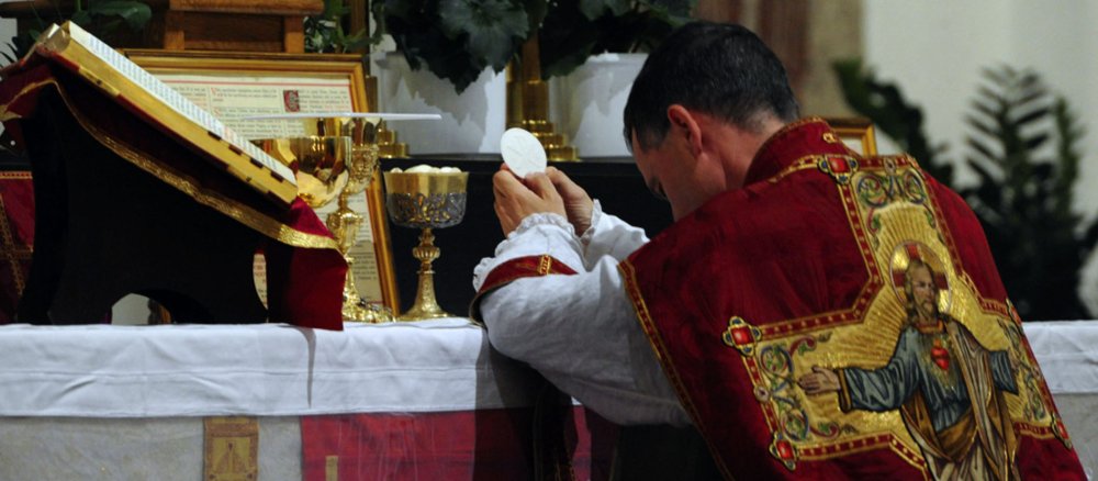 Ein Priester macht eine Kniebeuge vor der konsekrierten Hostie