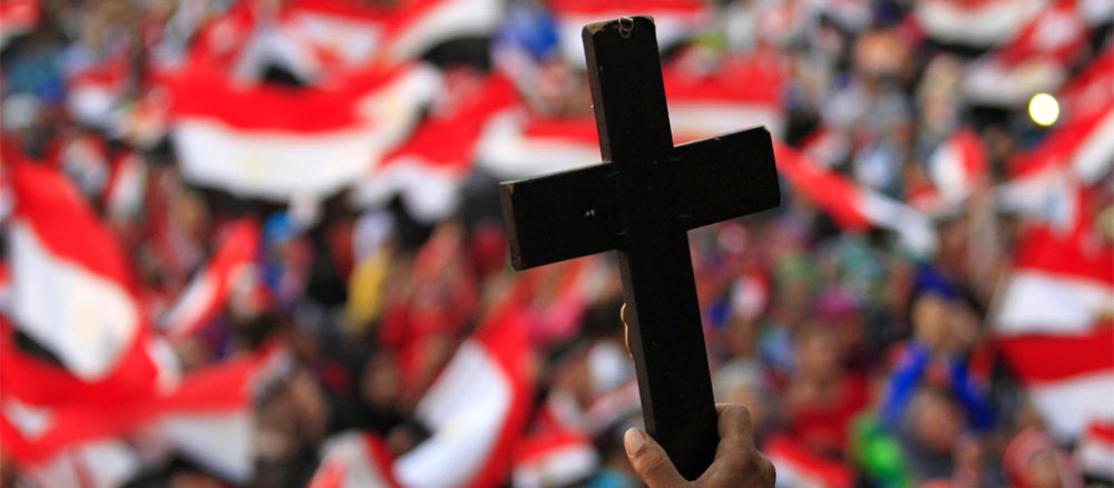 Ein Kreuz vor einem Meer von ägyptischen Flaggen.