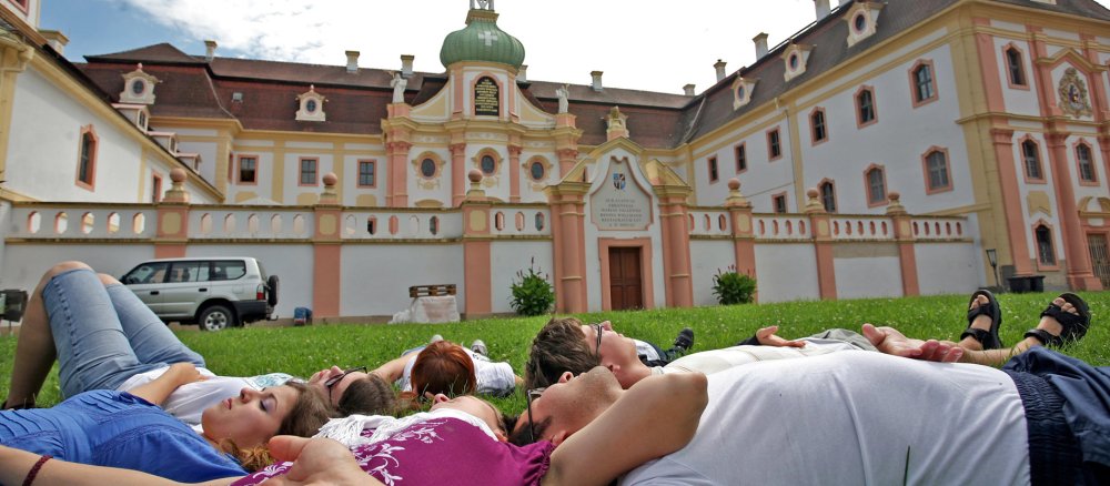 Jugendliche liegen vor dem Kloster Marienthal in Ostritz im Gras.