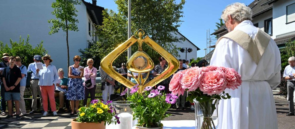 Eine Monstranz steht auf einem mit Blumen geschmückten Altar bei einer Statio während einer Fronleichnams-Prozesion
