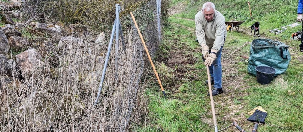 Andreas Sege befreit den Weg um die Kirche um Gras.
