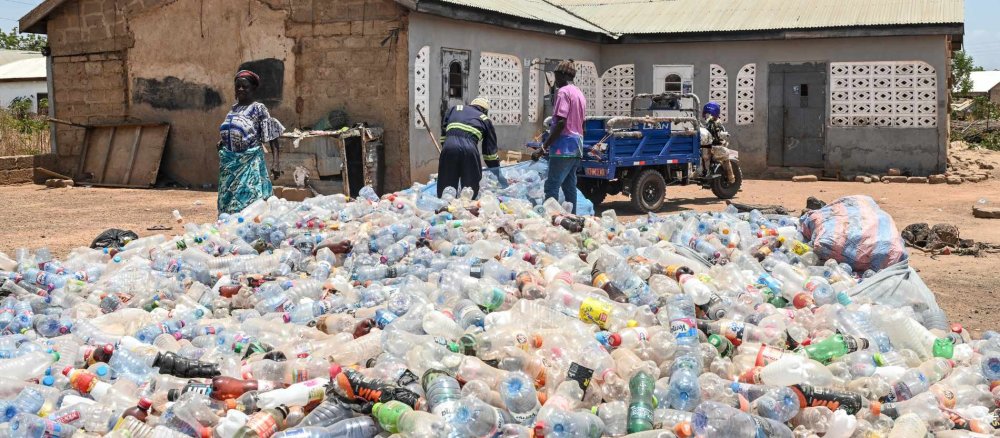 Yaro Seidu (m.) und sein Partner Al Hassan schieben leere Plastikflaschen zu einem 50 Kilo schweren Netz zusammen, am 26. März 2026 in Tamale (Ghana).