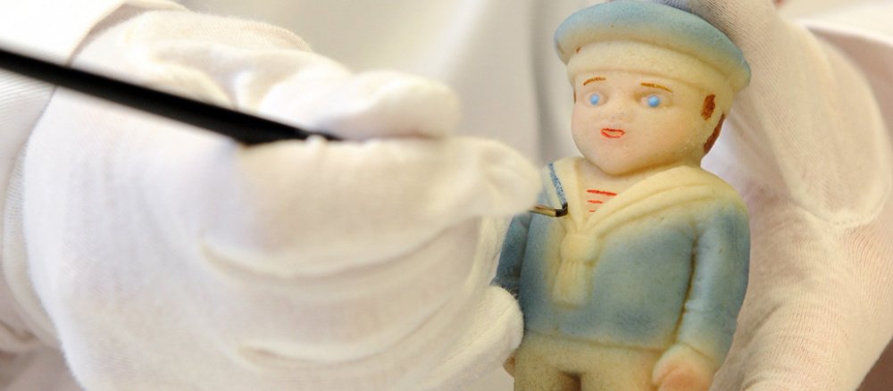 Eine Mitarbeiterin der Lübecker Manufaktur Niederegger bemalt einen Marzipan-Seemann.
