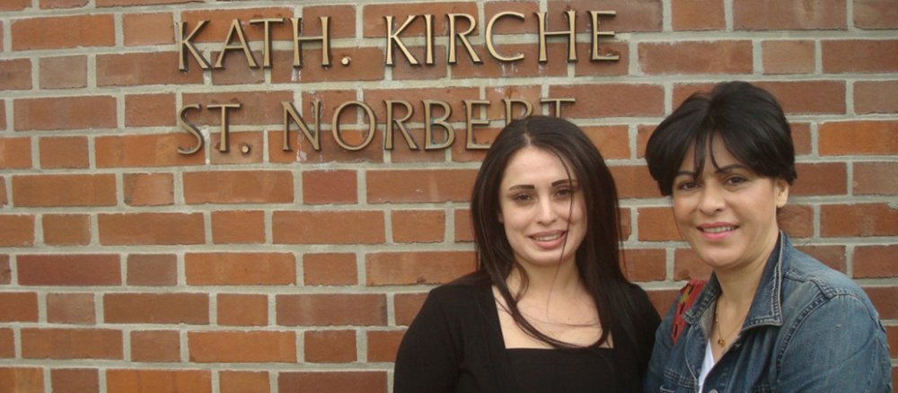Zwei Frauen, die vor dem Bürgerkrieg in Syrien geflohen sind, vor der katholischen Kirche Sankt Norbert im Grenzübergangslager Friedland (Niedersachsen).