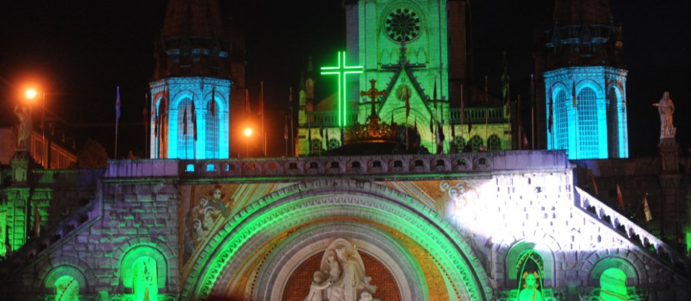 Die Rosenkranzbasilika in Lourdes wird in Grün und Blau angestrahlt.