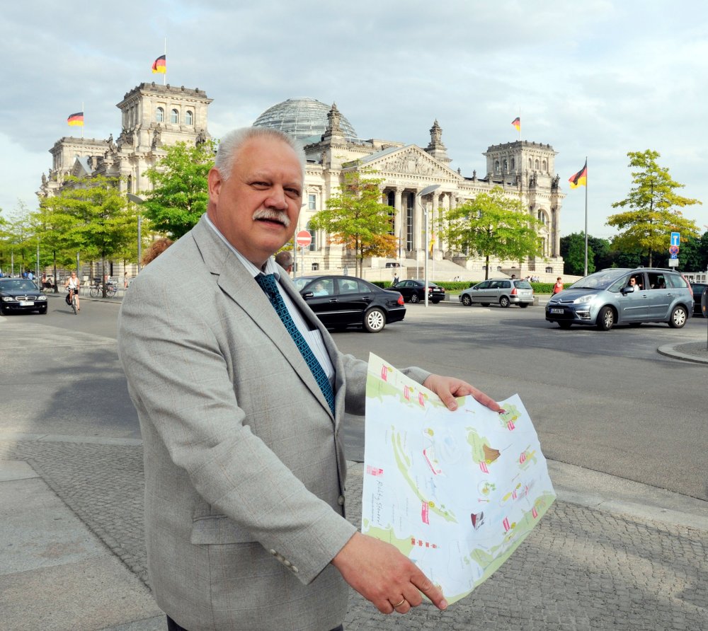 Ein Mann mit einer Landkarte in der Hand steht vor dem Deutschen Bundestag.