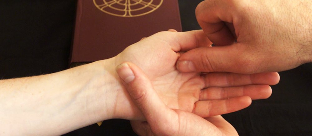 Ein Priester macht mit Öl ein Kreuzzeichen in die Hand einer Frau.