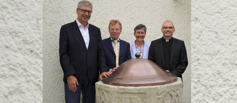 Die Leitung der Pfarrei Herz Jesu in Lenzburg und Historiker Josef Kunze stehen am Taufstein.