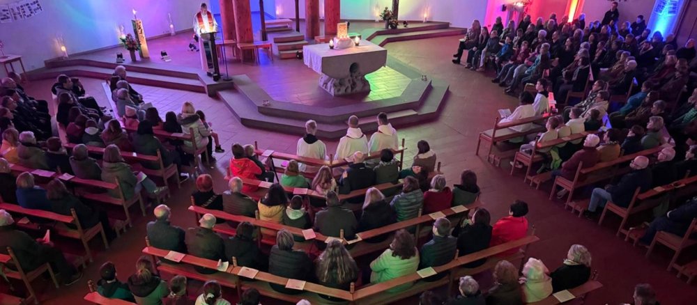 In der in blaues und rotes Licht getauchten Kirche sind die Bänke gefüllt.