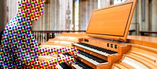 Ein Organist sitzt am Spieltisch einer Orgel und improvisiert.