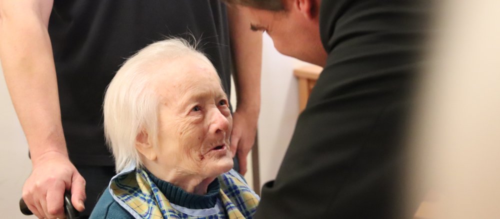 Eine alte Frau schaut Bischof Oster an.