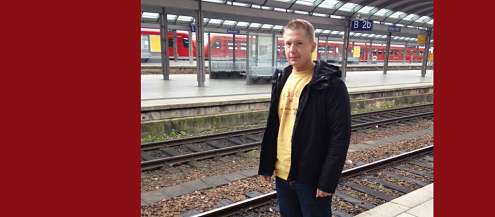Blonder junger Mann am Bahngleis