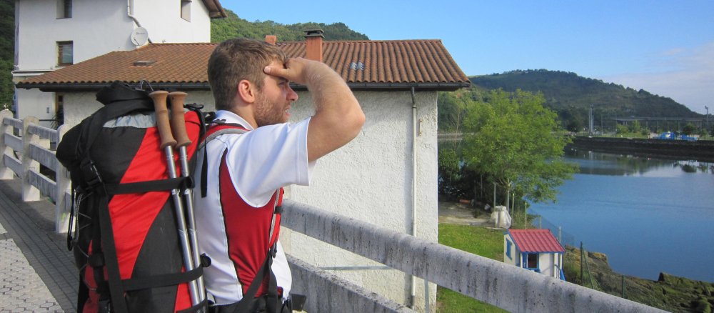 Ein Pilger mit einem Wanderrucksack blickt in die Ferne