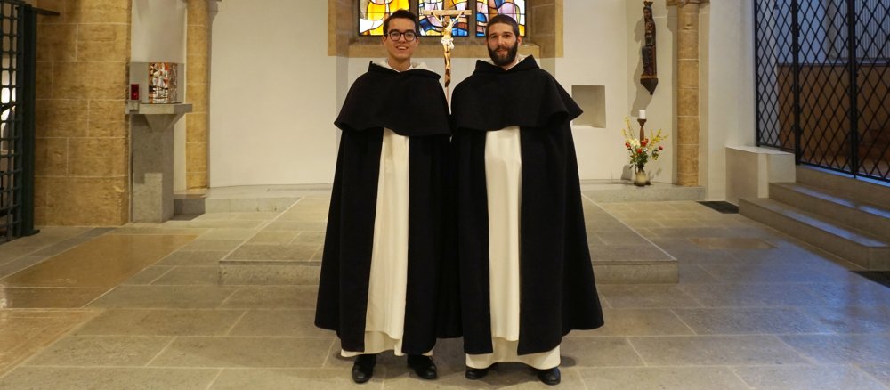 Zwei Dominikaner stehen im Habit in einer Kirche