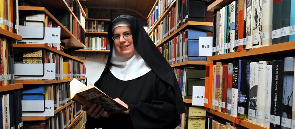 Eine Schwester im Habit in einer Bibliothek