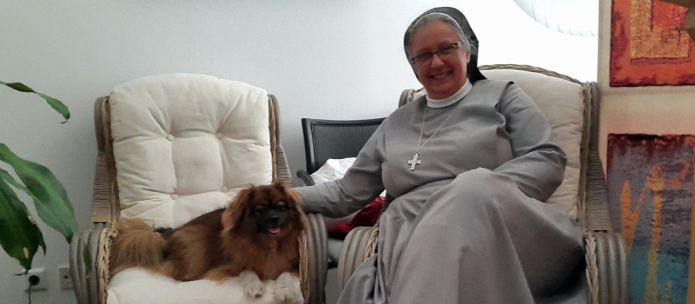 Eine Ordensfrau und ein Hund sitzen nebeneinander.